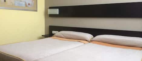 A double bed with a headboard, a bedside table, and a framed picture on the wall.