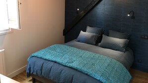 Une chambre à coucher avec un lit, une fenêtre et un mur sombre avec un plafond en pente.