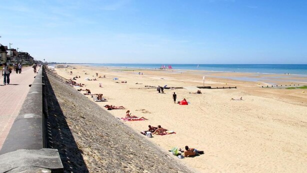 A beach with people sunbathing and walking along a paved walkway. - Apartment in France with Balcony or Terrace (Cabourg)