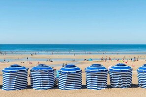 A beach with striped umbrellas and people in the distance.