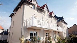 A two-story building with a balcony on the second floor. - Apartment in France with Balcony or Terrace (Cabourg)