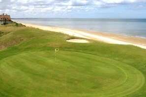 A golf course with a sand bunker and a flagstick. - Apartment in France with Balcony or Terrace (Cabourg)