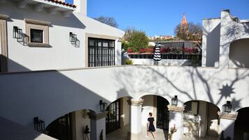 Un patio con suelo de baldosas, arcos y una persona caminando.