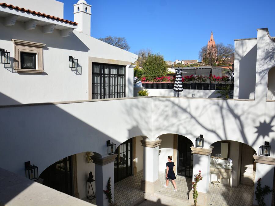 Un patio con suelo de baldosas, arcos y una persona caminando.