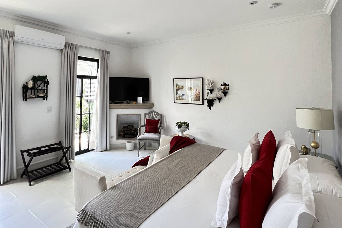 A spacious bedroom with a large bed, a TV, and a fireplace.