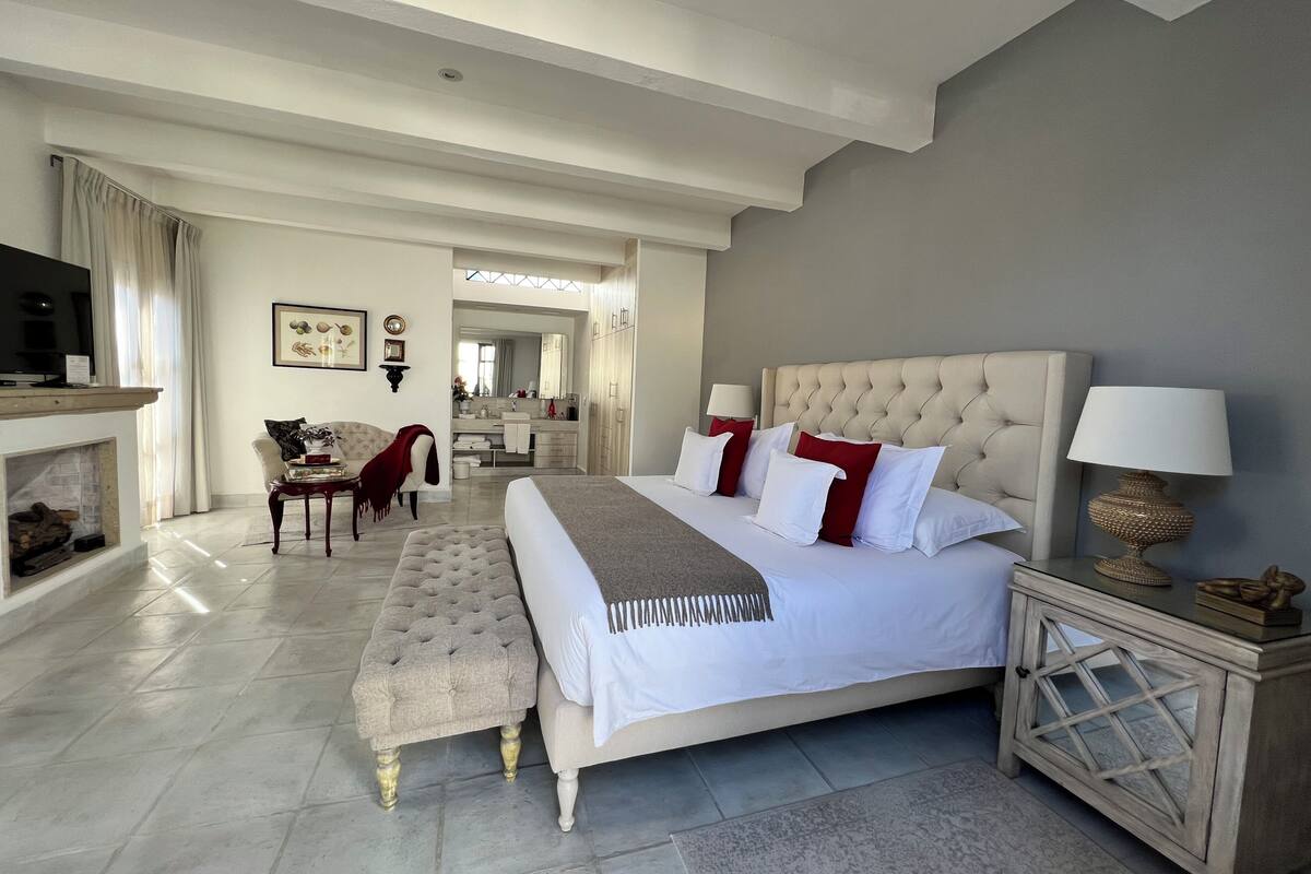 A spacious bedroom with a large bed, a seating area, and a view into the bathroom.