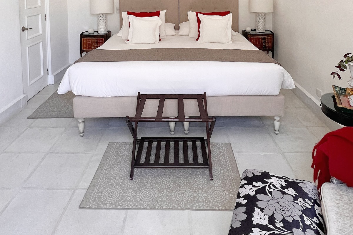 A neatly arranged bedroom with a large bed, two bedside tables, a bench, and a small side table.