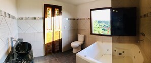 Un baño con inodoro, lavamanos con lavabo negro, bañera y ventana con vistas a zonas verdes.