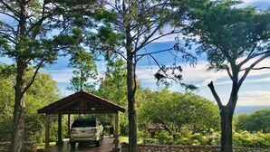 A covered parking area with a stone wall and a pavilion. - Casa Chumamaya (Merlo)