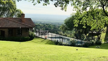 Uma casa com telhado de cerâmica, deck cercado e vista para um vale.