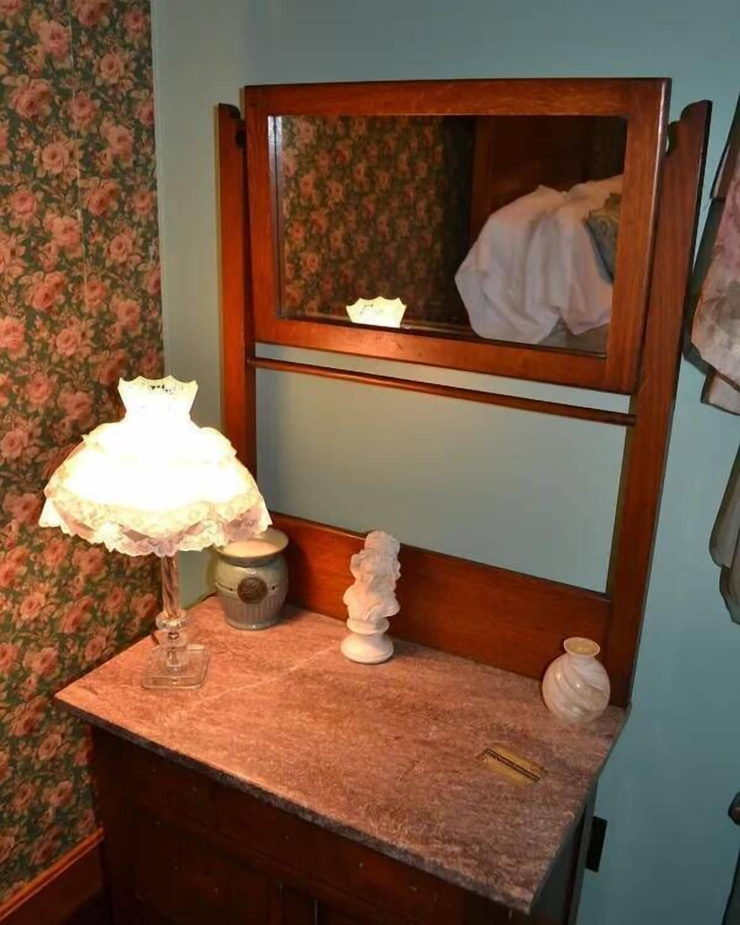 A bathroom vanity with a mirror, a lamp, and decorative items.