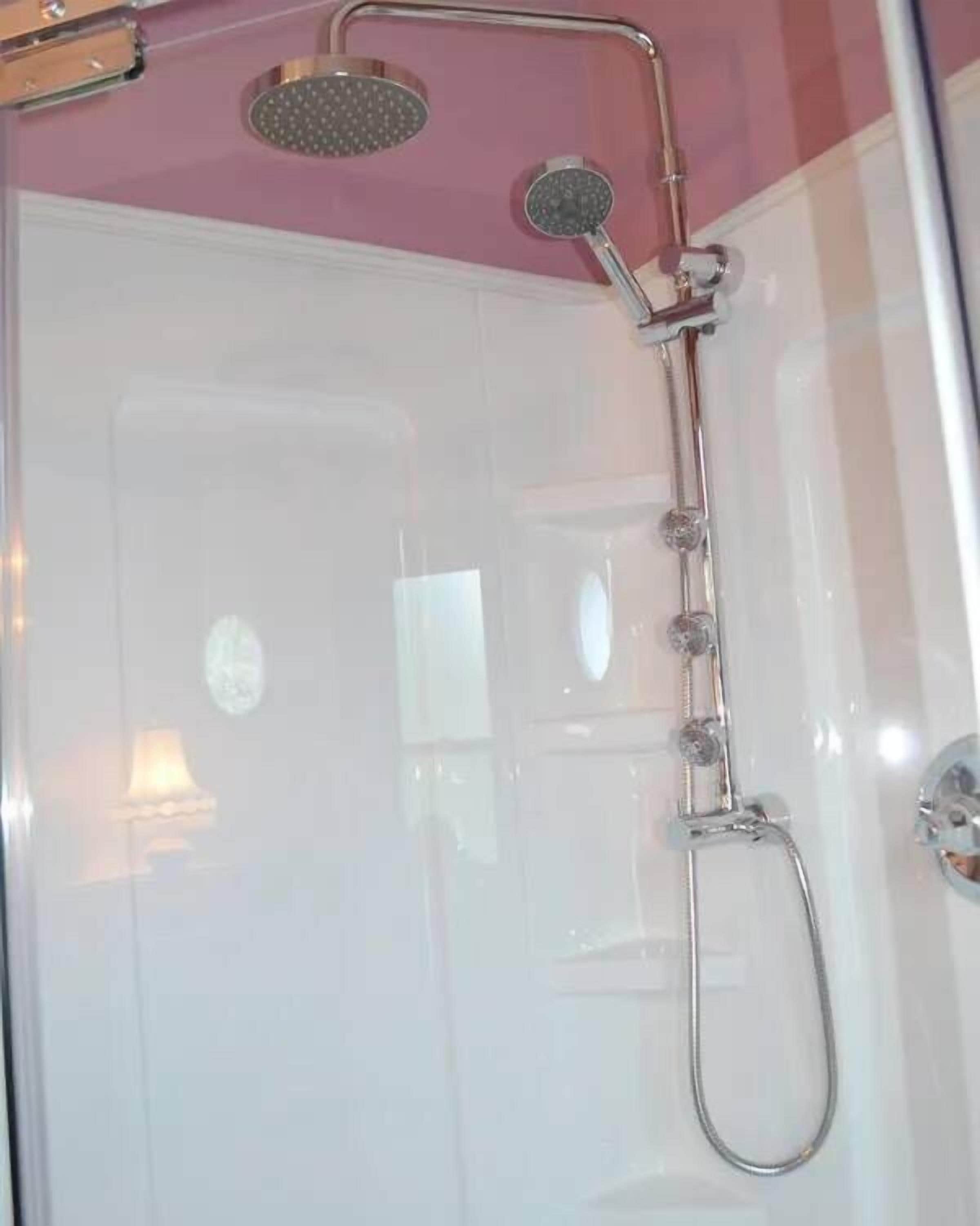 A shower with a handheld showerhead and a fixed showerhead mounted on the wall.