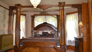 A four-poster canopy bed with a wooden headboard, a chandelier, and a radiator on the floor. - The Conner House B&B (Prairie du Rocher)