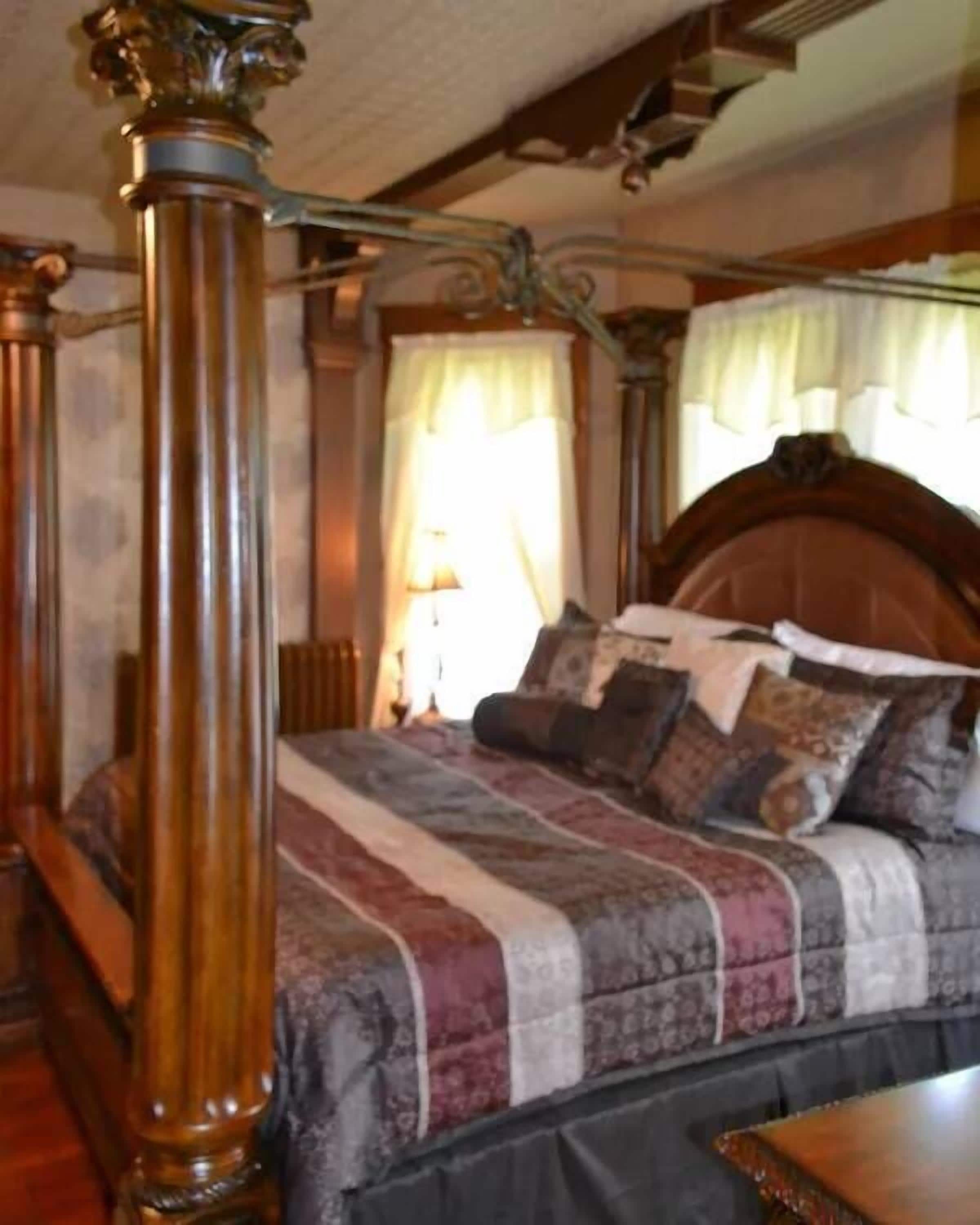 A bedroom with a four-poster bed, a wooden headboard, and a nightstand.