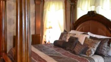 A bedroom with a four-poster bed, a wooden headboard, and a nightstand.