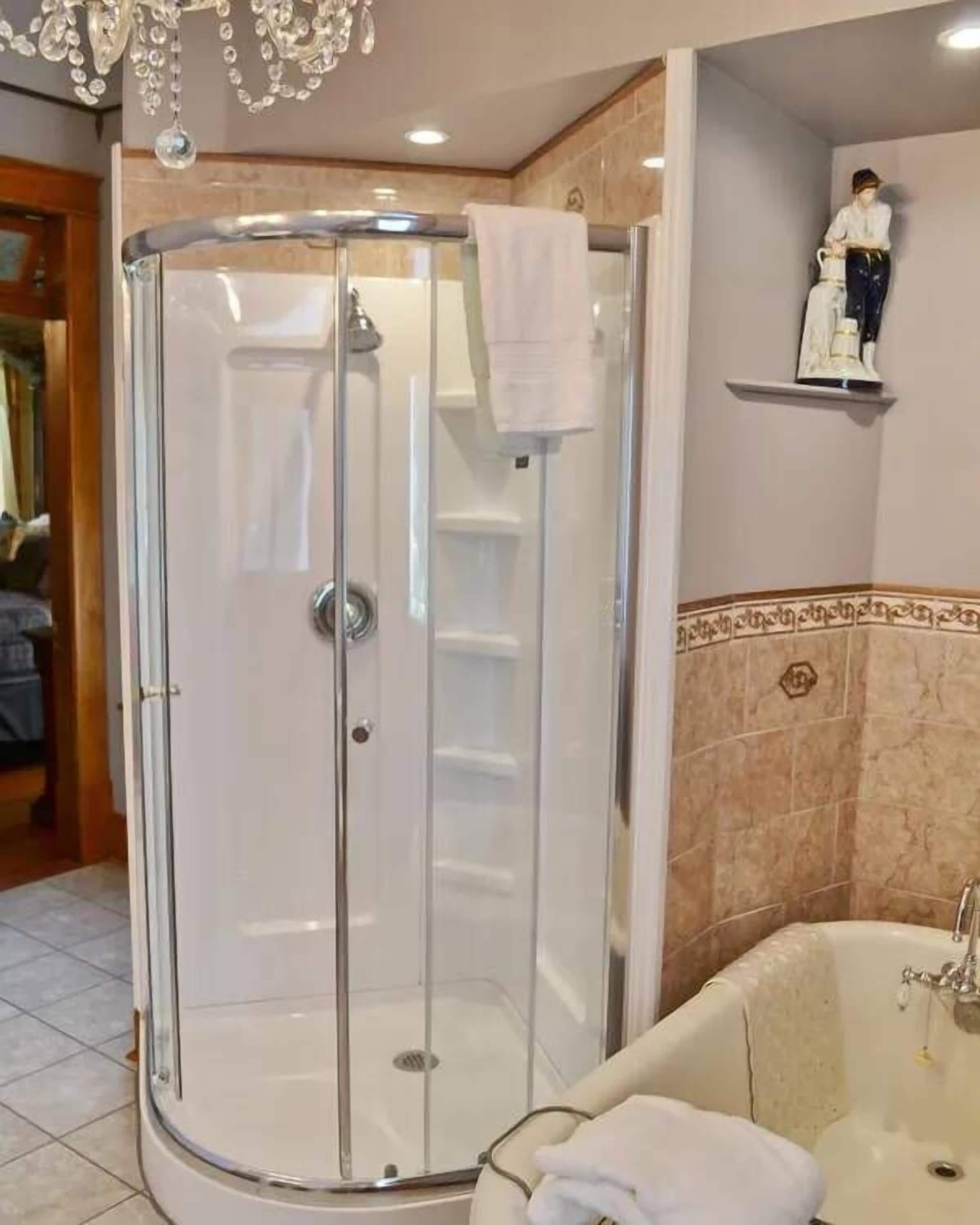 Une salle de bain dotée d’une douche à parois de verre, d’une baignoire et d’un mur recouvert de carreaux de marbre.