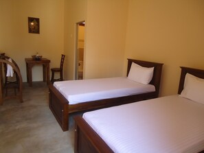 A bedroom with two wooden beds, a small wooden table with a chair, and a framed picture on the wall. - New Sanmi Resort (Malabe)