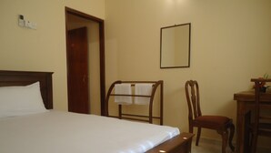 Habitación de hotel con una cama grande, una silla de madera, un escritorio con una silla y un espejo en la pared.