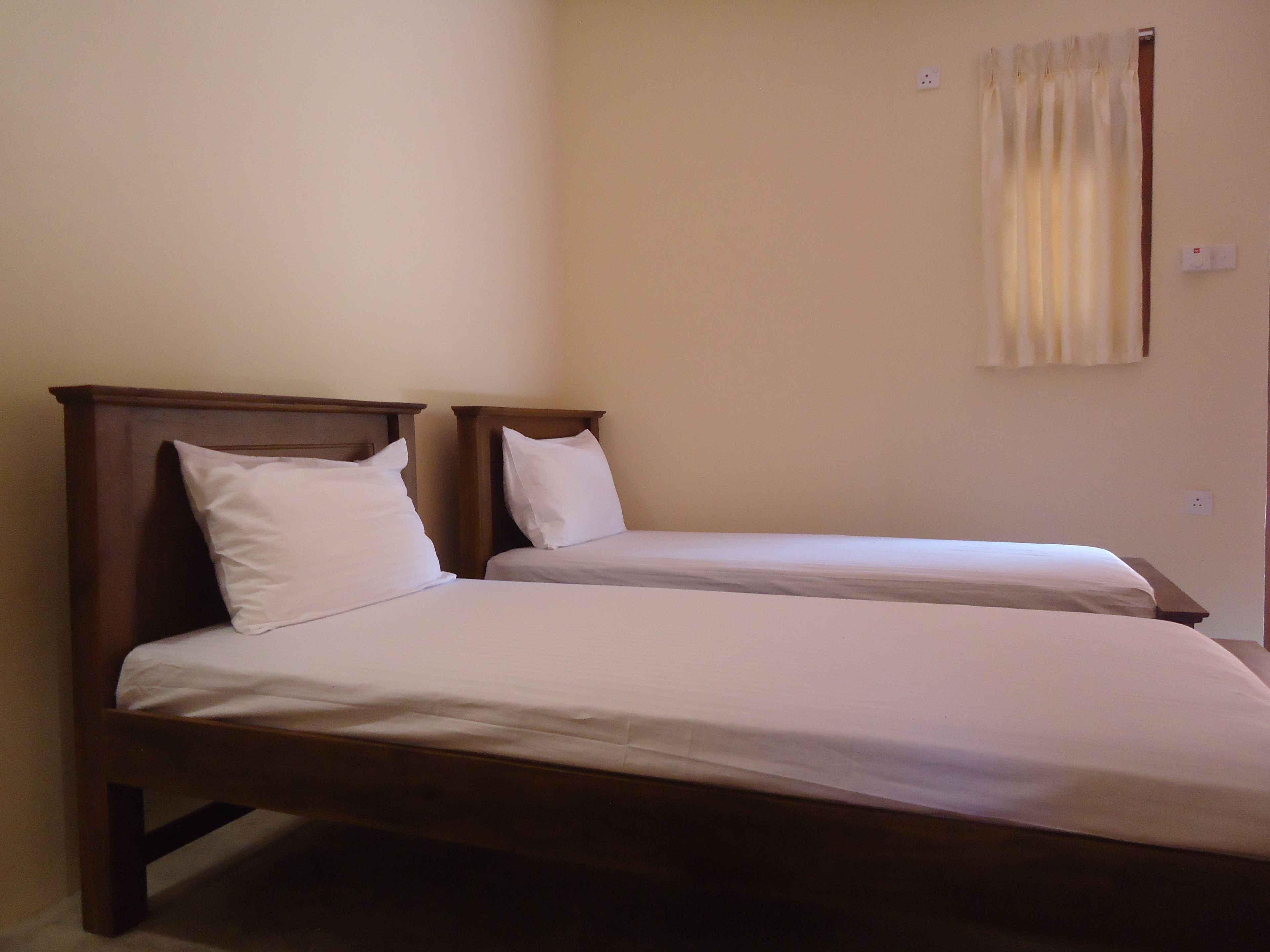 Ein Zimmer mit zwei Einzelbetten, jeweils mit Holz Kopfteilen und weißen Bettwäsche.