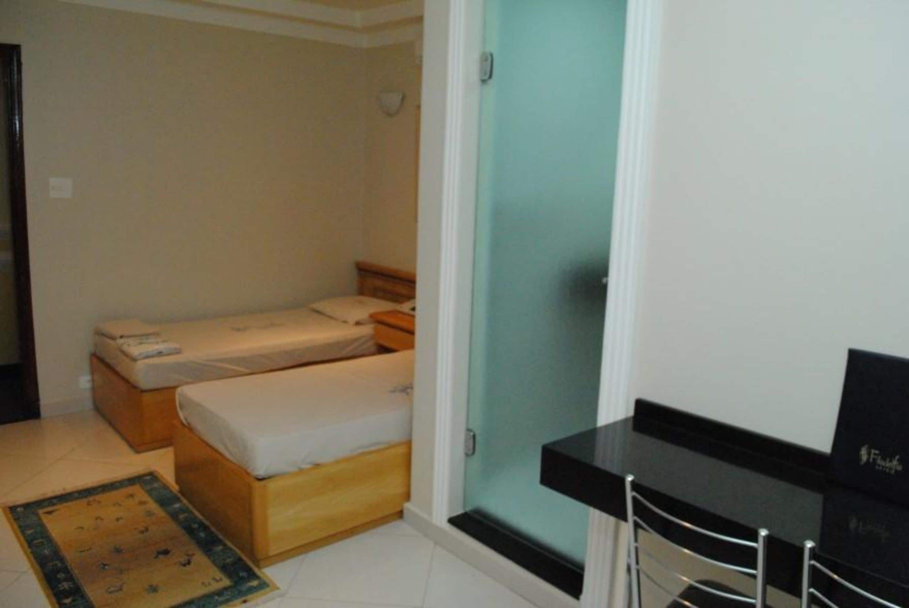 A small, compact room with a bed, a desk, and a chair.