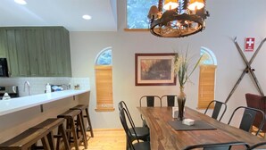 A dining area with a wooden table and chairs, a vase with plants, and a painting on the wall.