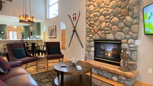 A cozy living room with a stone fireplace, a sofa, and a coffee table.