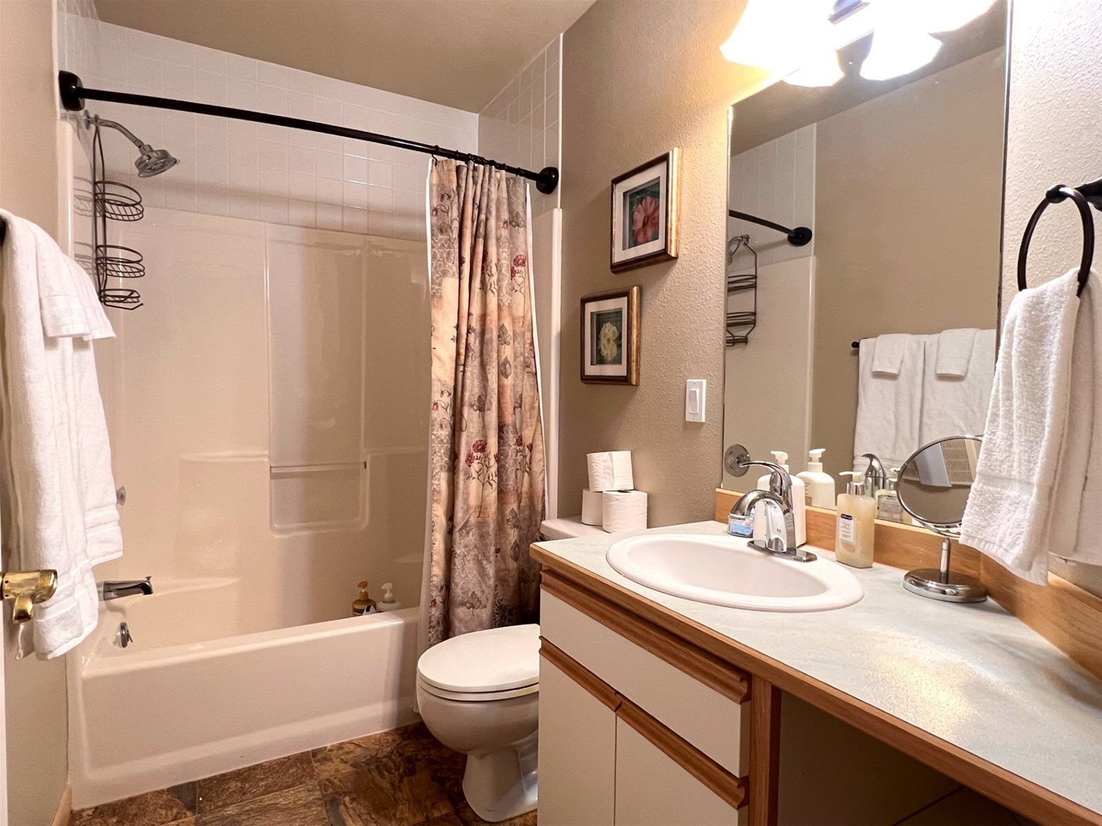 A bathroom with a bathtub, toilet, and sink. There are towels and toiletries on the counter.