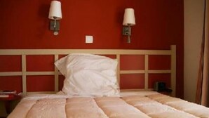 A hotel room with a bed, two wall-mounted lamps, and a red wall. - Flat - 2 rooms - 5 persons (Saint-Raphaël)