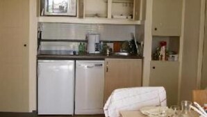 A compact kitchen with a dishwasher, a microwave, and a sink. There is a dining table with a white tablecloth and a few dishes. - Flat - 2 rooms - 5 persons (Saint-Raphaël)