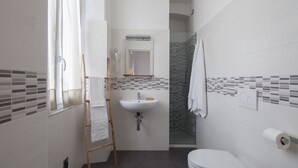 Une salle de bain moderne avec un lavabo blanc, des toilettes et un espace douche.