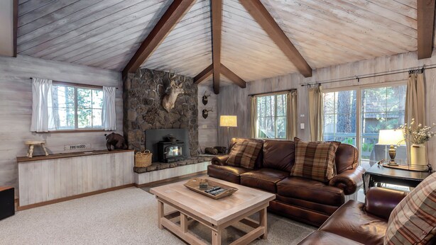 Ein gemütliches Wohnzimmer mit Kamin aus Stein, einer Ledersofa und einem Holztisch.