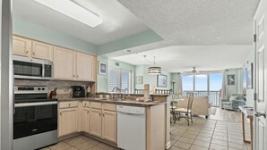 A modern kitchen with built-in appliances, a large island, and a dining area with a view. - Luxury 15th Floor Corner Unit, Jacuzzi Tub, Lazy River | Crescent Shores - S 1506 (North Myrtle Beach)