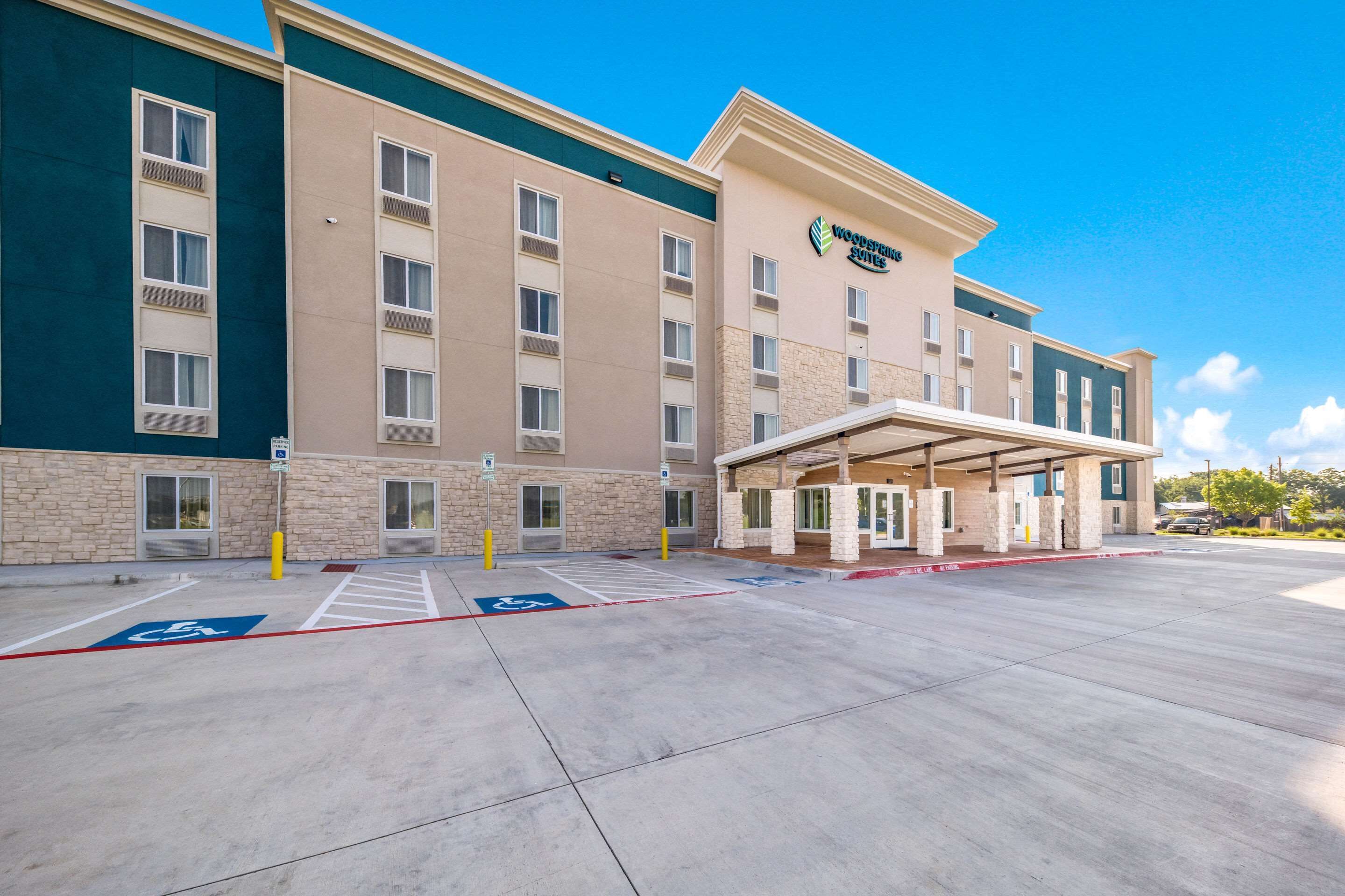 A hotel with a modern facade, multiple entry points, and designated handicapped parking spaces.