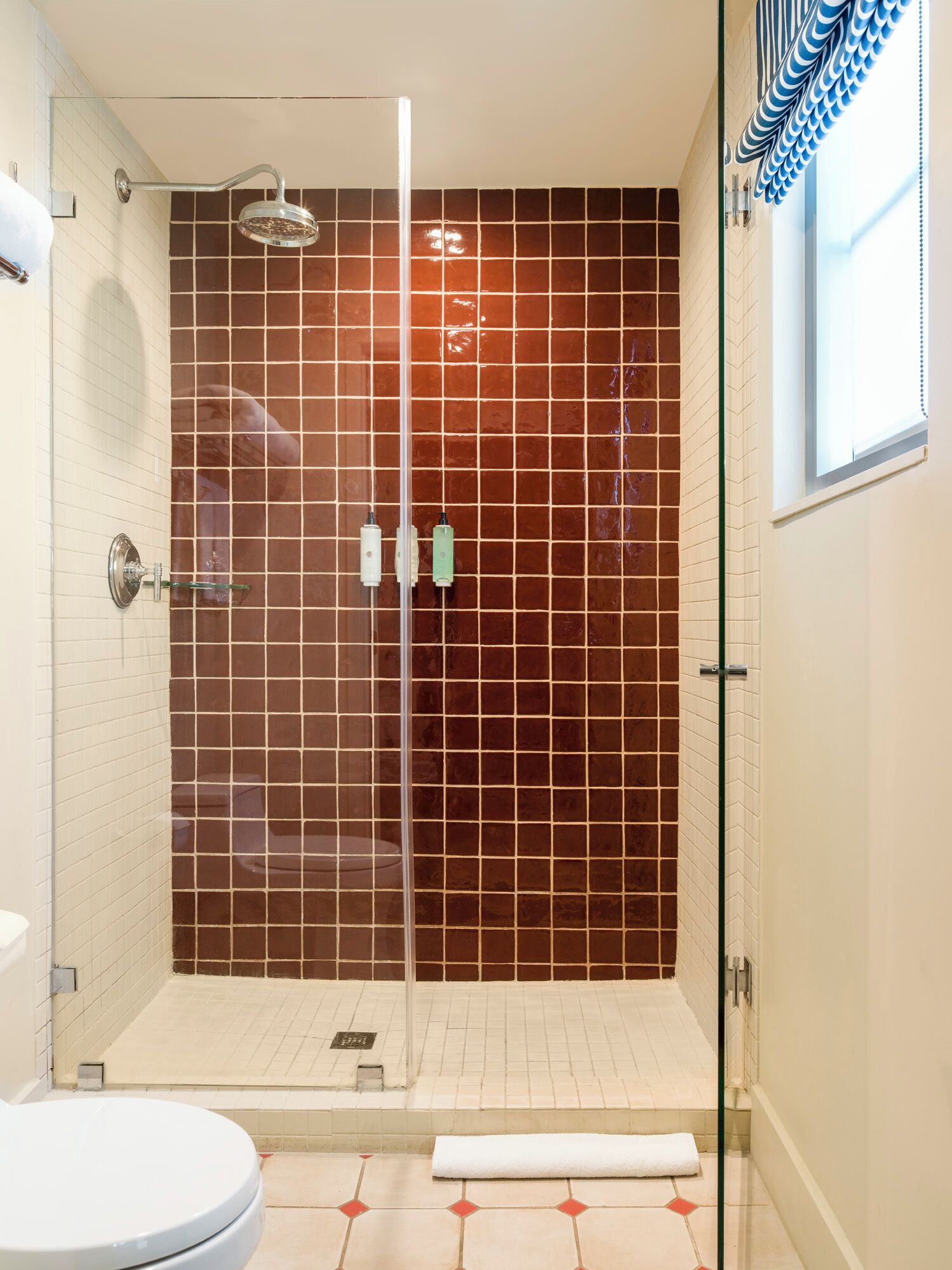 Une salle de bain moderne avec une douche à parois de verre, des toilettes blanches et un sol carrelé.