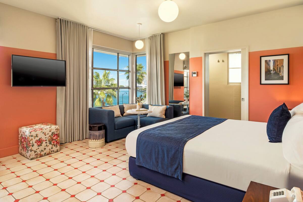 A hotel room with a bed, a sofa, a TV, a window with a view, and a bathroom.