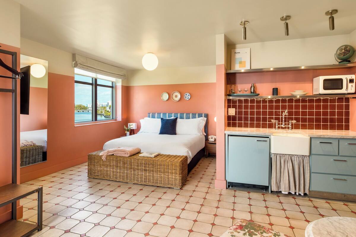 A bedroom with a bed, bedside table, and a view of the city.