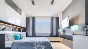 A modern bedroom with a large bed, a TV, and a window with curtains. - Joseph's Place @ Avenir Condo w/ NETFLIX (Cebu City)
