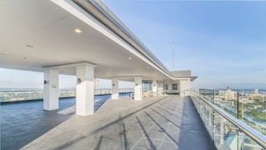 An open terrace with a glass railing, large pillars, and a view of the cityscape. - Joseph's Place @ Avenir Condo w/ NETFLIX (Cebu City)