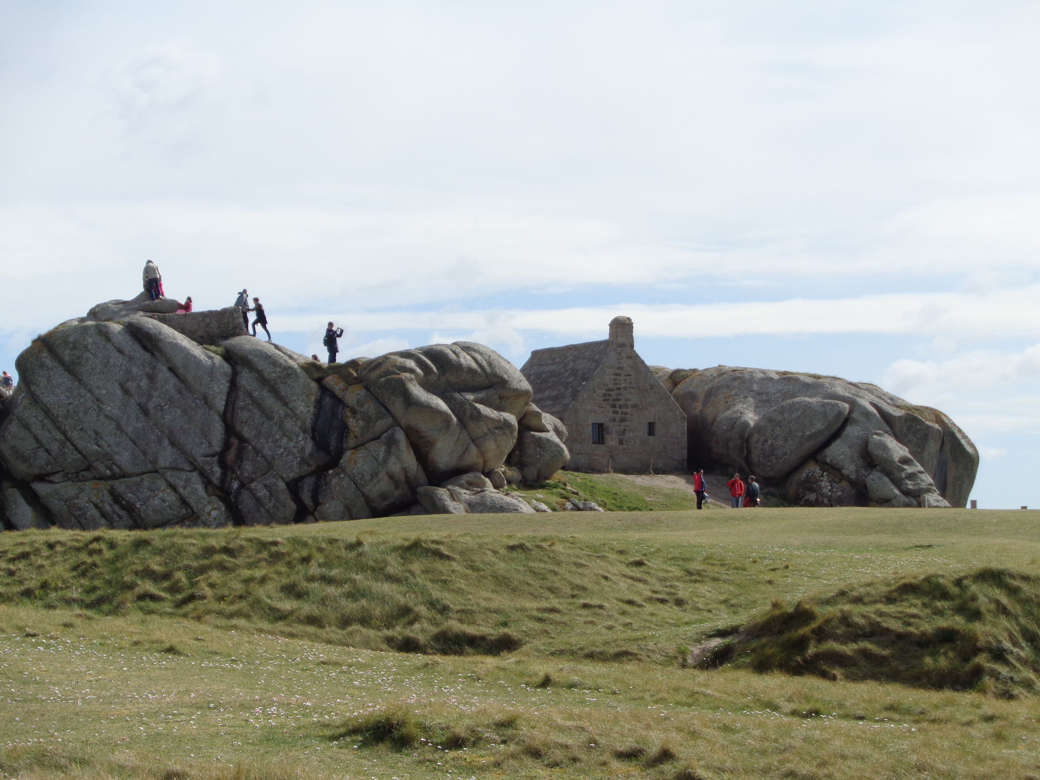 A large rock formation with a small stone building on top.