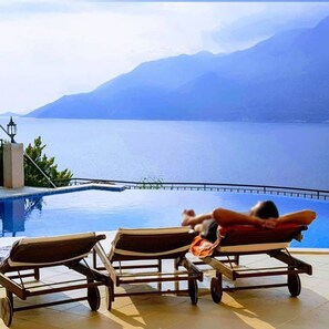 A poolside area with lounge chairs and a view of a lake and mountains. - Villa Mavi Manzara / Luxury, secluded private villa (Kas)