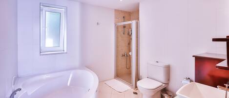 A modern bathroom with a large bathtub, a glass-enclosed shower, a toilet, and a sink.