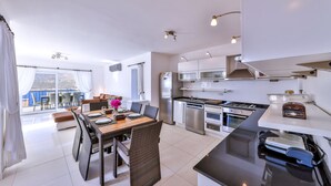 A modern kitchen with stainless steel appliances, a dining area with wicker chairs, and a view of the outdoors. - Villa Mavi Manzara / Luxury, secluded private villa (Kas)
