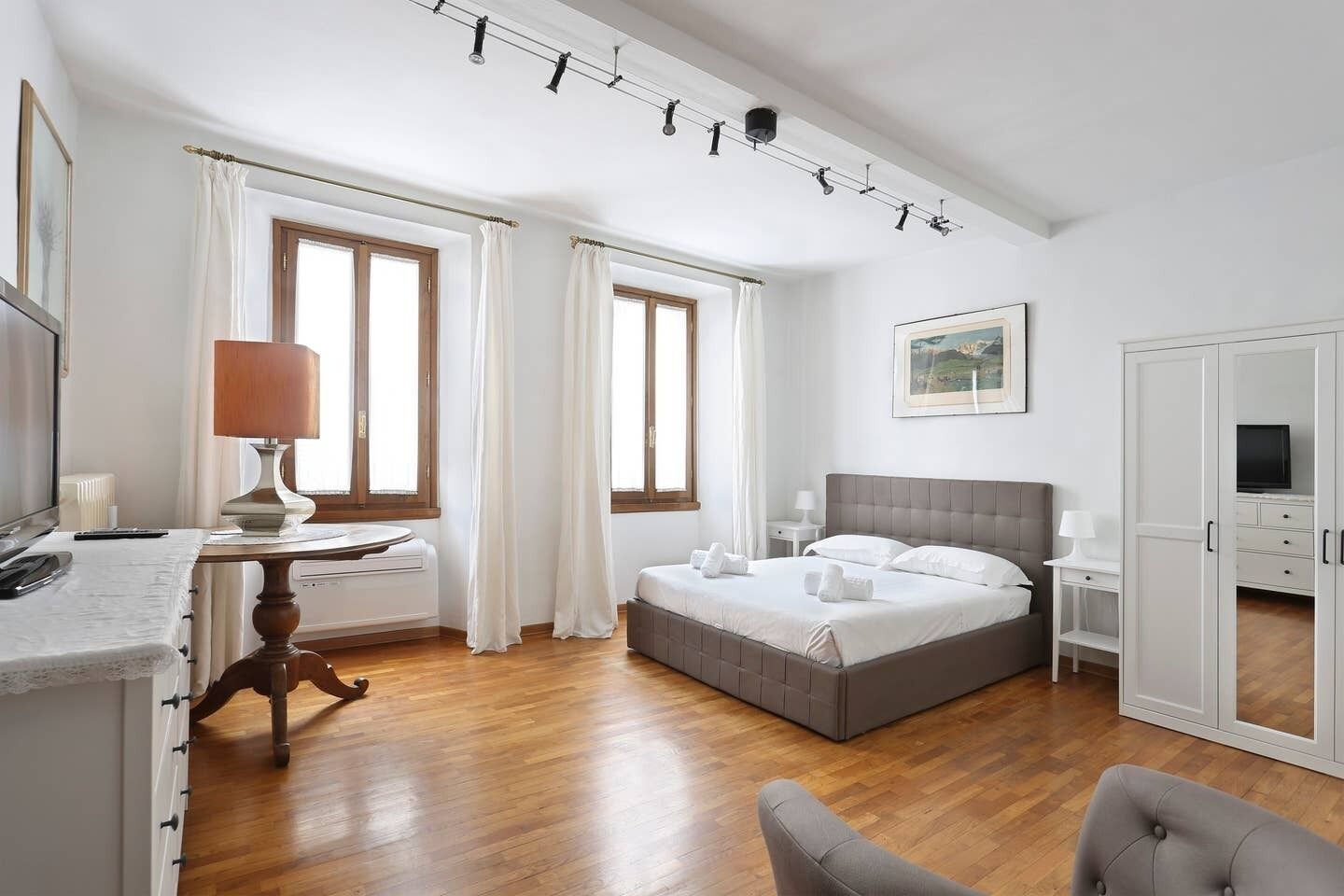 Une chambre à coucher comprenant un lit, un bureau, une chaise, une armoire et un luminaire fixé au plafond.
