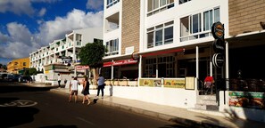 Vista de una calle con un edificio que tiene varias fachadas comerciales, incluyendo un restaurante llamado 'Little Germany' y un cartel de 'MAGNERS'.