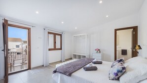 A bedroom with a bed, a bedside table, a mirror, a wardrobe, and a balcony with a chair. - Casa Sa Placeta by JS Villas (Sa Pobla)