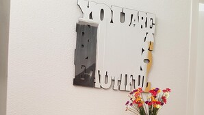 A vintage-style cabinet with two doors, a decorative sign above, and a pink vase with flowers on top. - Los Cristianos Apartment Nirvana Tenerife South (Los Cristianos)