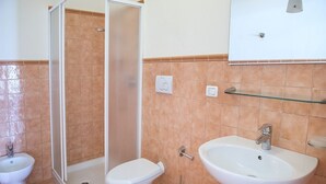 Ein Badezimmer mit Dusche, Toilette, Bidet und Waschbecken.