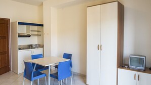 Eine kleine Küche mit Esstisch und Stühlen, einem Fernseher auf einem Schrank und einem Kleiderschrank.