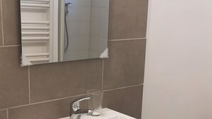 A bathroom with a white sink, a mirror, and a shower.