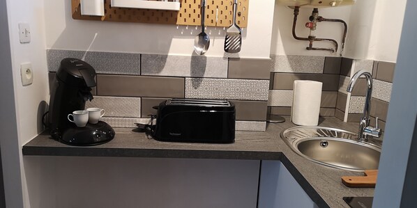Een keuken met een koffiezetapparaat, broodrooster en spoelbak.